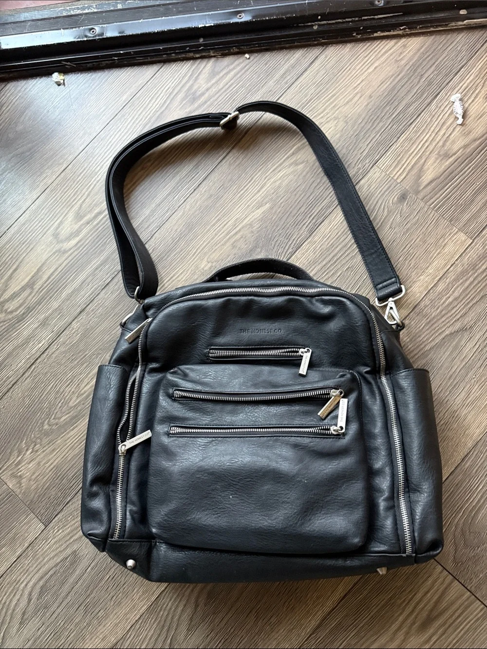 The Honest Company Black Vegan Leather Diaper Bag backpack model cross country